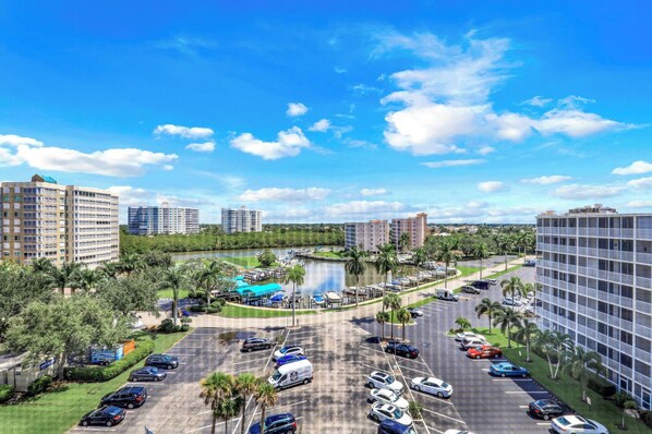 A hotel complex with multiple high-rise buildings, a marina with boats, and a parking lot with several vehicles.