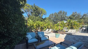 Una terraza con mobiliario exterior, incluyendo dos sofás y una mesa, rodeada de abundante vegetación y árboles.