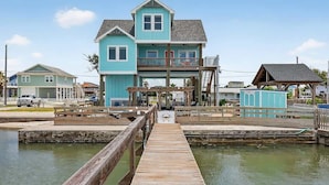 A waterfront property with a dock leading to a house with a balcony.