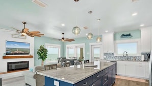 A modern kitchen with a central island, white cabinetry, and a view to the outside.