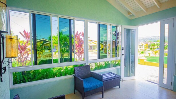 A room with a large window overlooking a garden and a view of a residential area. - 3BR Villa in Drax Hall Country Club (St. Ann's Bay)