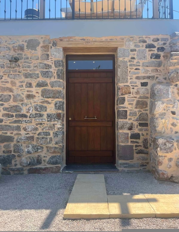 Un bâtiment en pierre avec une porte en bois et une petite fenêtre au-dessus.
