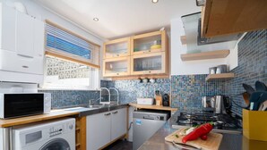 A modern kitchen with a washing machine, microwave, and stove. - Trewirgie - Central with sea views (St Ives)
