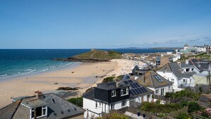 A coastal town with a sandy beach, houses with solar panels, and a clear view of the sea. - Trewirgie - Central with sea views (St Ives)