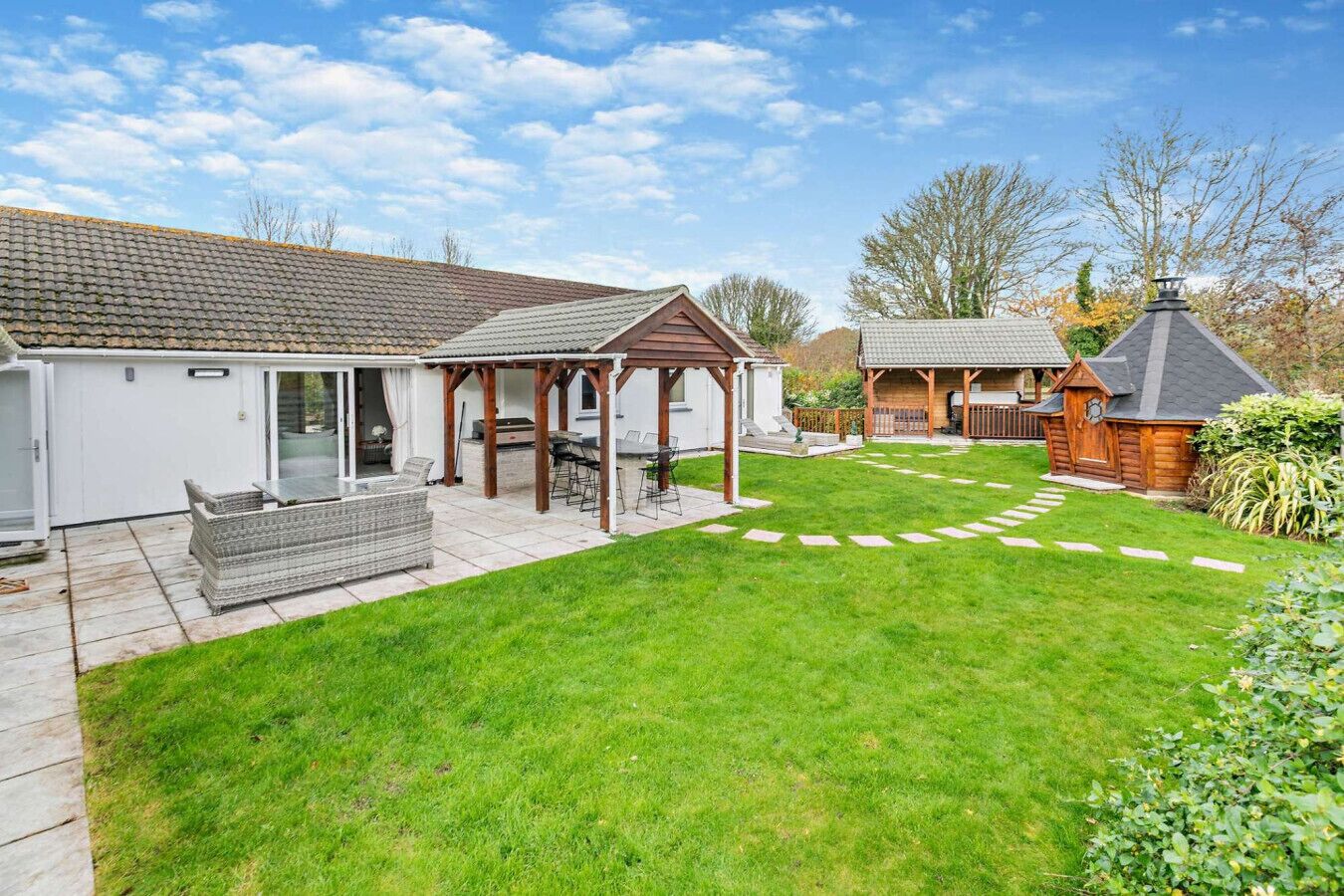 A backyard with a patio, a pergola, and a small wooden structure.