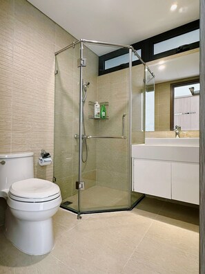 Une salle de bain moderne avec une douche à parois de verre, des toilettes et un lavabo surmonté d’un miroir.