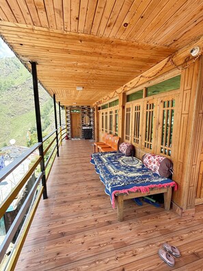 A wooden deck with a bed, pillows, and a pair of slippers. - Viraaj Homestay  (Rajgarhi)