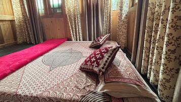 Una habitación con paredes de madera, una cama con ropa de cama estampada y cortinas con diseños florales.