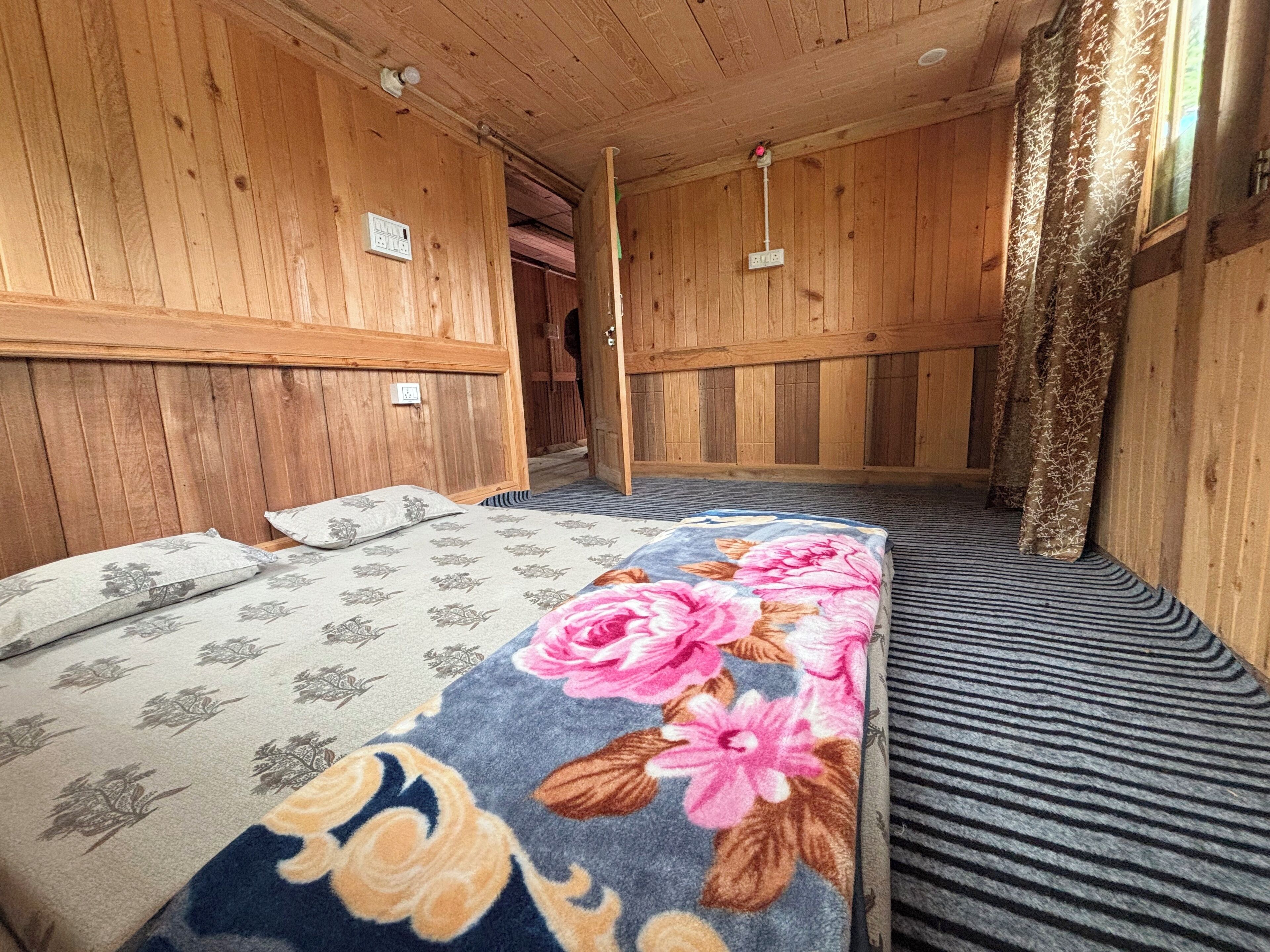 Une pièce en bois avec un lit, un banc et une porte donnant sur une autre pièce.