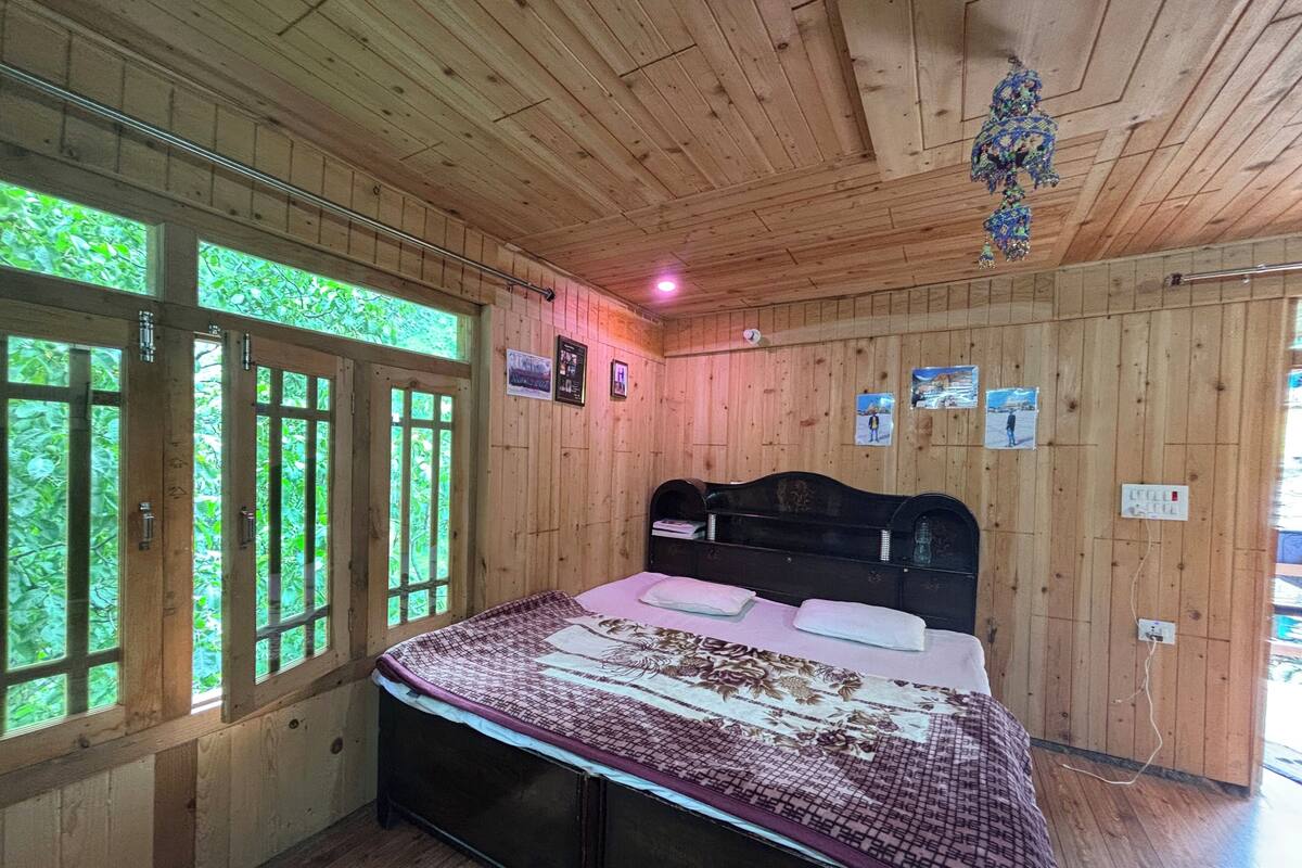 A wooden-paneled room with a bed, large windows, and a wooden ceiling.