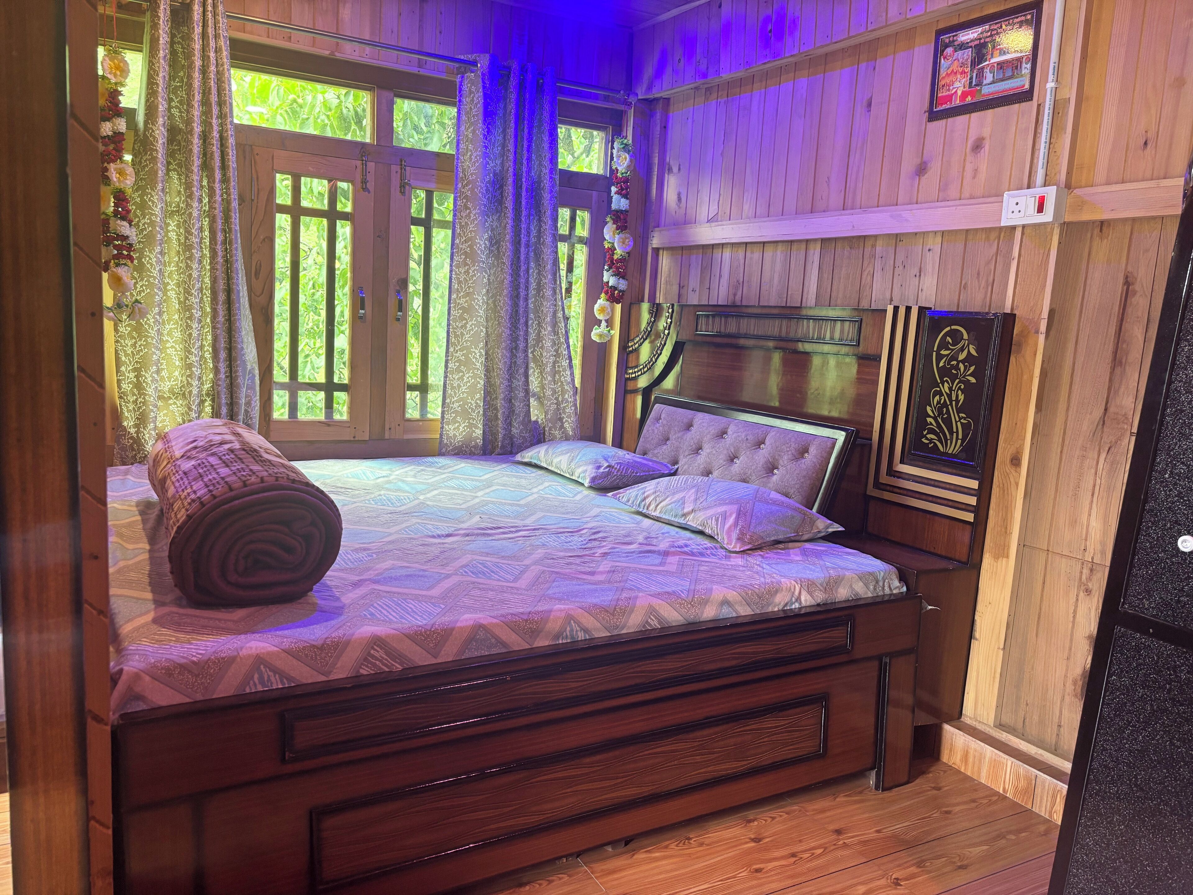 Ein Zimmer mit Holzboden, einem Bett, Vorhängen und einem Fenster.