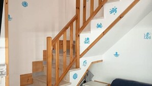 A staircase with wooden railings and white steps, leading to a landing area with a small white cabinet and a dark blue sofa.