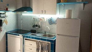 A kitchen with a stove, sink, cabinets, and a refrigerator.