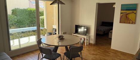A modern living room with a dining area, a TV, and a painting on the wall.