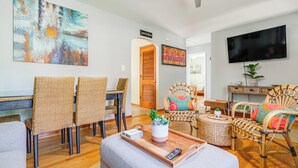 A modern living room with wicker furniture, a flat-screen TV, and a large abstract painting. - < 1 Mi to Colonial Beach: Coastal Gem w/ 2 Porches (Colonial Beach)