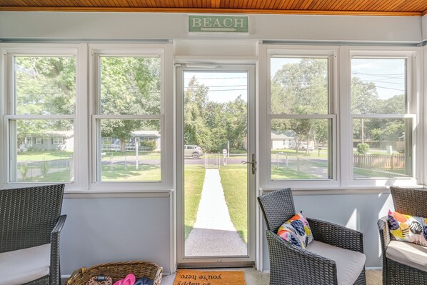A room with wicker furniture, a door leading outside, and a 'BEACH' sign above the door. - < 1 Mi to Potomac: Cozy Colonial Beach Cottage (Colonial Beach)