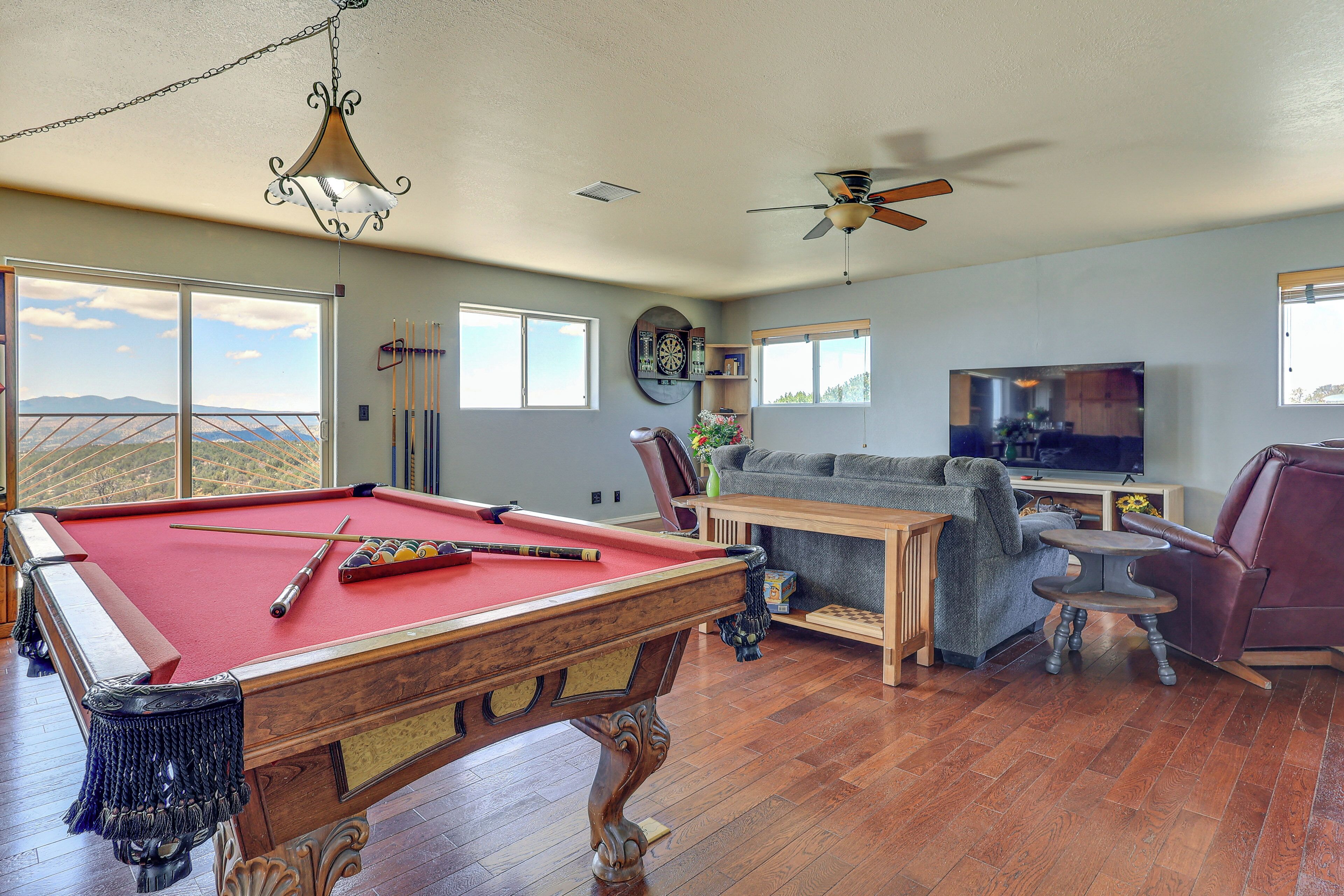 A spacious living room with a pool table, a sofa, a television, and a ceiling fan.