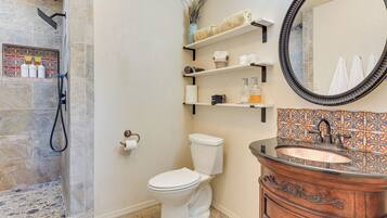 A bathroom with a shower, toilet, vanity, and shelves with toiletries.