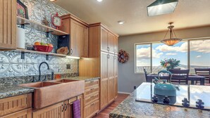 A kitchen with wooden cabinets, a granite countertop, a sink, and a kettle. - Panoramic Vistas and Spacious: Silver City Escape (Silver City)