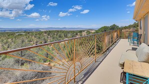 A balcony with a view of a mountainous landscape, a wooden table, and blue chairs. - Panoramic Vistas and Spacious: Silver City Escape (Silver City)