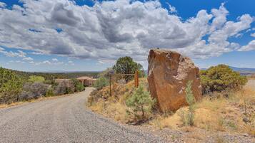 A gravel road leading to a rustic building with a large rock formation nearby.