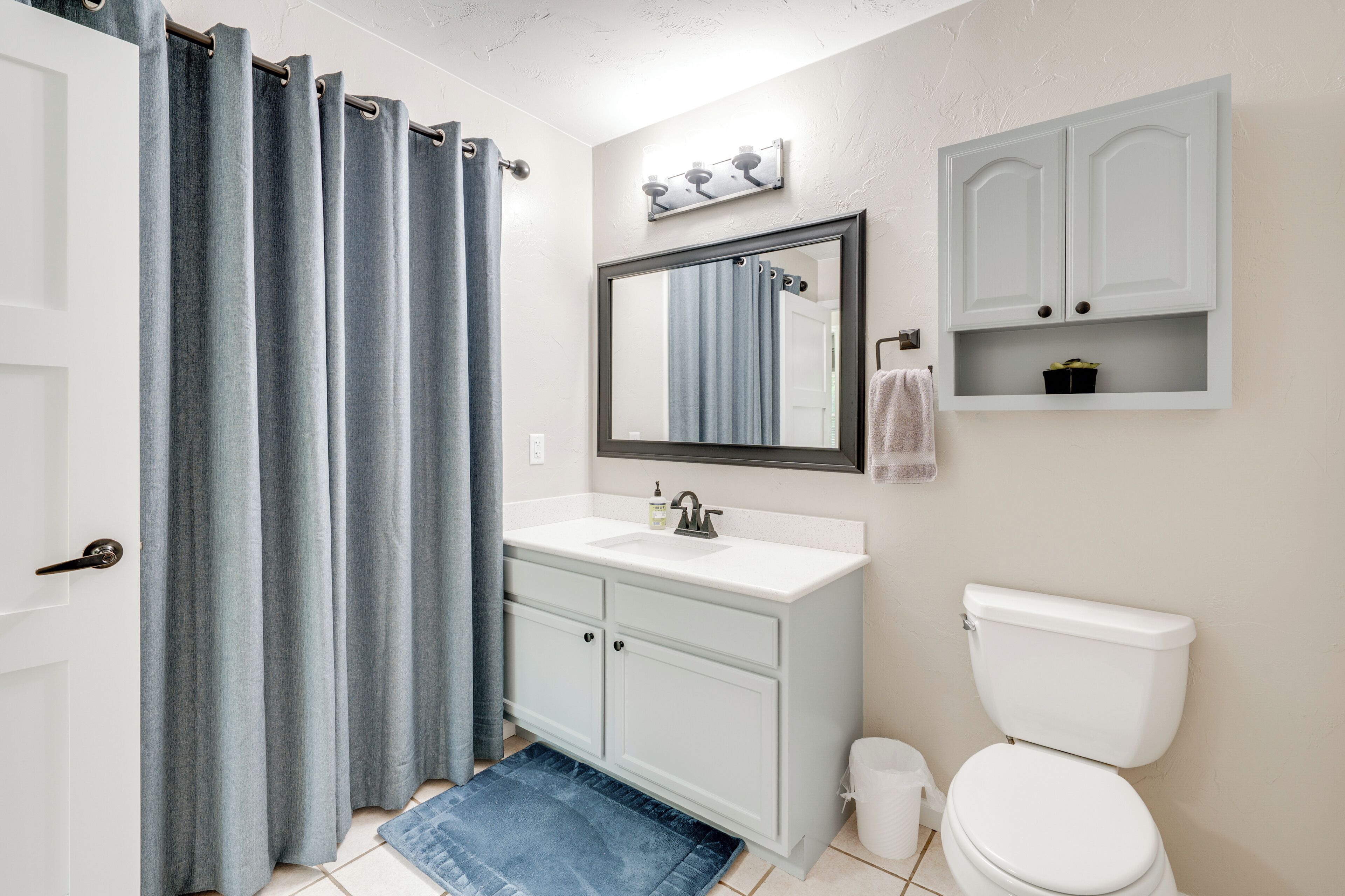 A bathroom with a white sink, a toilet, a mirror, and a shower curtain.