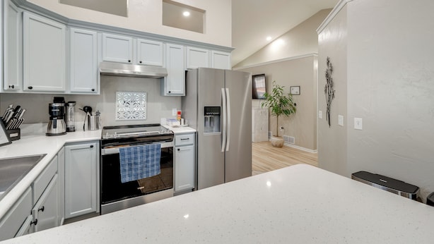 A modern kitchen with white cabinetry, stainless steel appliances, and a central island.