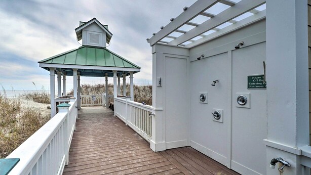 A wooden deck with a covered area and a sign indicating a restroom. - Marina & Pool: Roomy Golf-view Home in Southport (St. James)