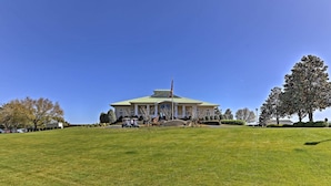 A large, historic building with a green roof and a central dome, surrounded by a well-maintained lawn and trees. - Marina & Pool: Roomy Golf-view Home in Southport (St. James)
