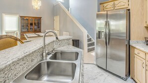A kitchen with granite countertops, stainless steel appliances, and a wooden cabinet. - Marina & Pool: Roomy Golf-view Home in Southport (St. James)