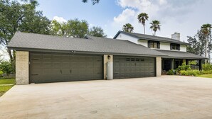 Een tweelaags huis met een grote garage, een overdekt terras en een verzorgd gazon.