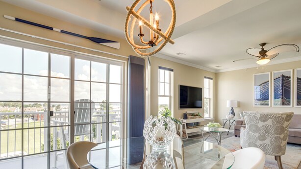 A spacious living room with a glass table, comfortable seating, a large TV, and a balcony with a view. - Walkable Condo w/ Drawbridge Views in Cambridge (Cambridge)