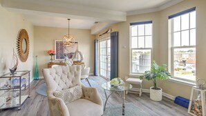 A spacious living room with a large armchair, a glass coffee table, and a view through large windows. - Walkable Condo w/ Drawbridge Views in Cambridge (Cambridge)