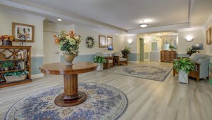 A spacious lobby with a round wooden table, multiple chairs, a patterned rug, and a bookshelf. - Walkable Condo w/ Drawbridge Views in Cambridge (Cambridge)