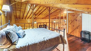 A wooden cabin interior with a bed, a dining area, and a door. - Secluded Lodge Stay: Day Trip to Audra State Park! (French Creek)