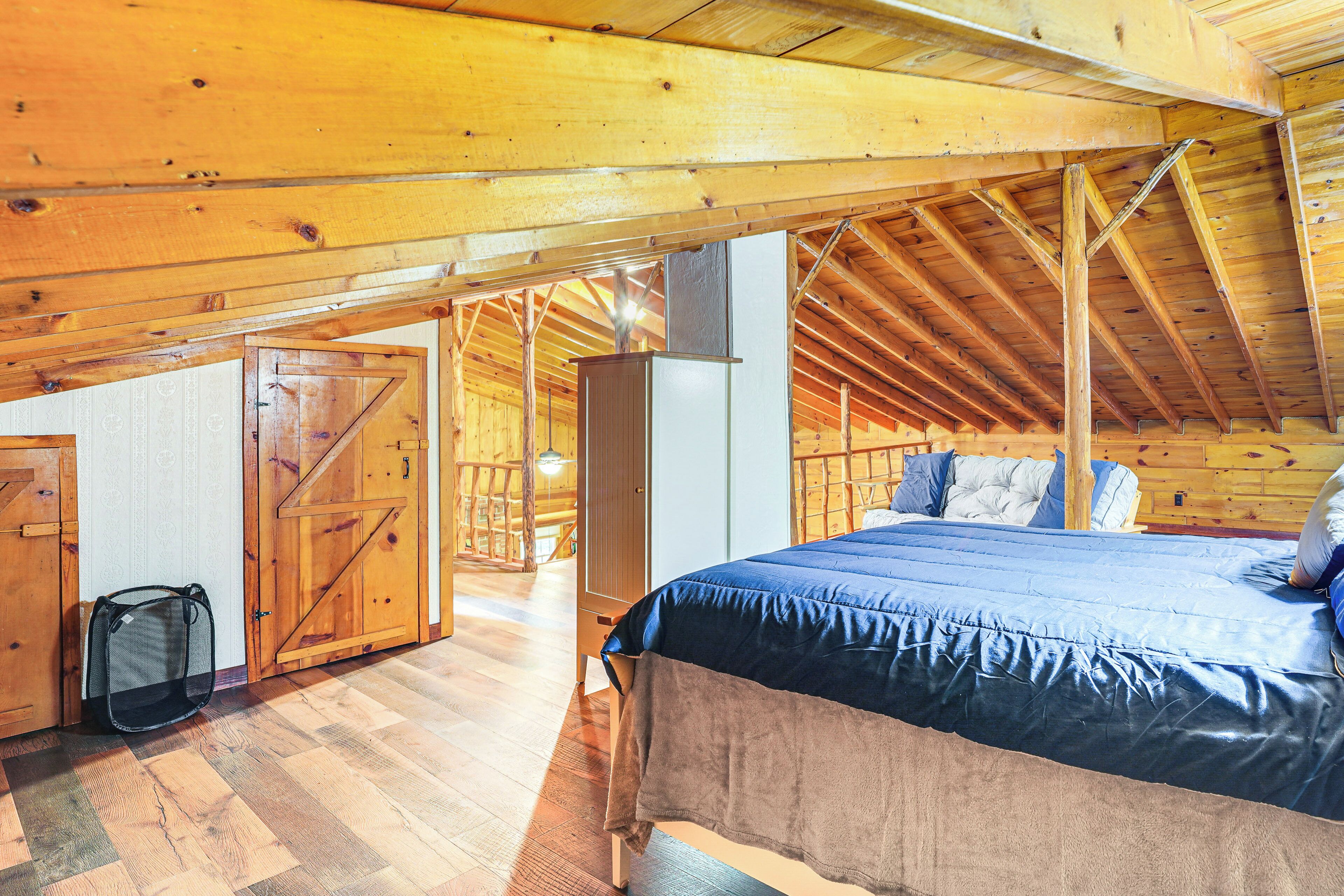 Camera da letto in una baita di legno con un letto, un armadio e una borsa appesa.