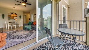 A spacious balcony with a glass door leading to a patio area, a ceiling fan, and a dining table with chairs.