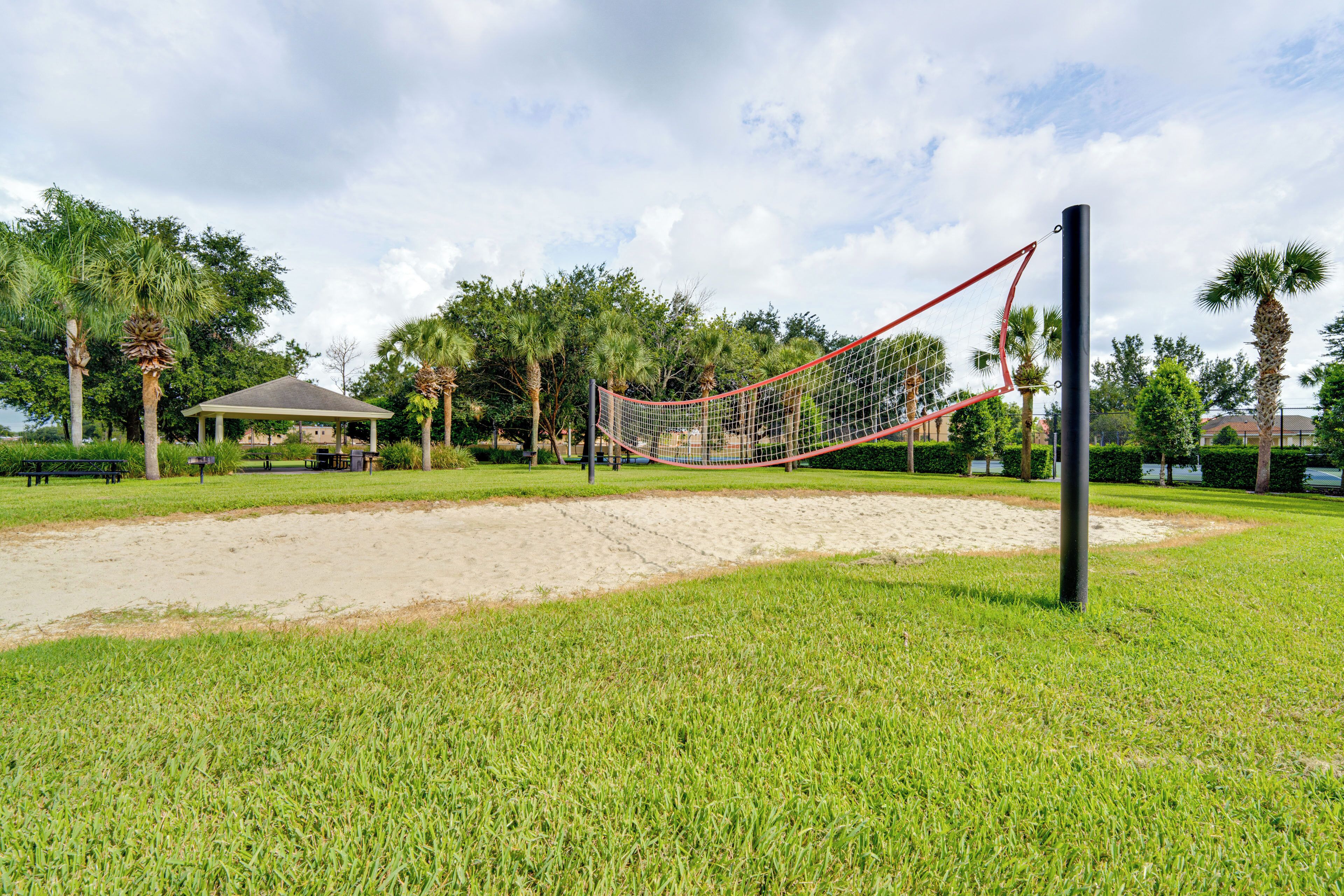 Una red de voleibol en un parque con un porche y palmeras al fondo.