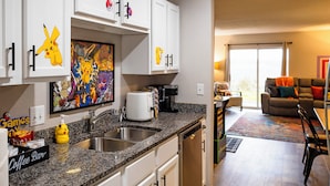 A kitchen with white cabinets, a coffee bar, and a dining area with a couch and chairs. - 'groovy Games Getaway' Holiday Stay in Branson! (Branson)