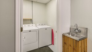 A compact laundry room with two washing machines, a sink, and a wooden cabinet. - Shared Outdoor Space: Quaint Studio in Fredonia (Fredonia)