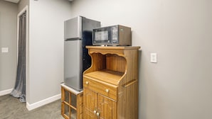 A compact kitchen with a refrigerator, microwave, and wooden cabinet. - Shared Outdoor Space: Quaint Studio in Fredonia (Fredonia)