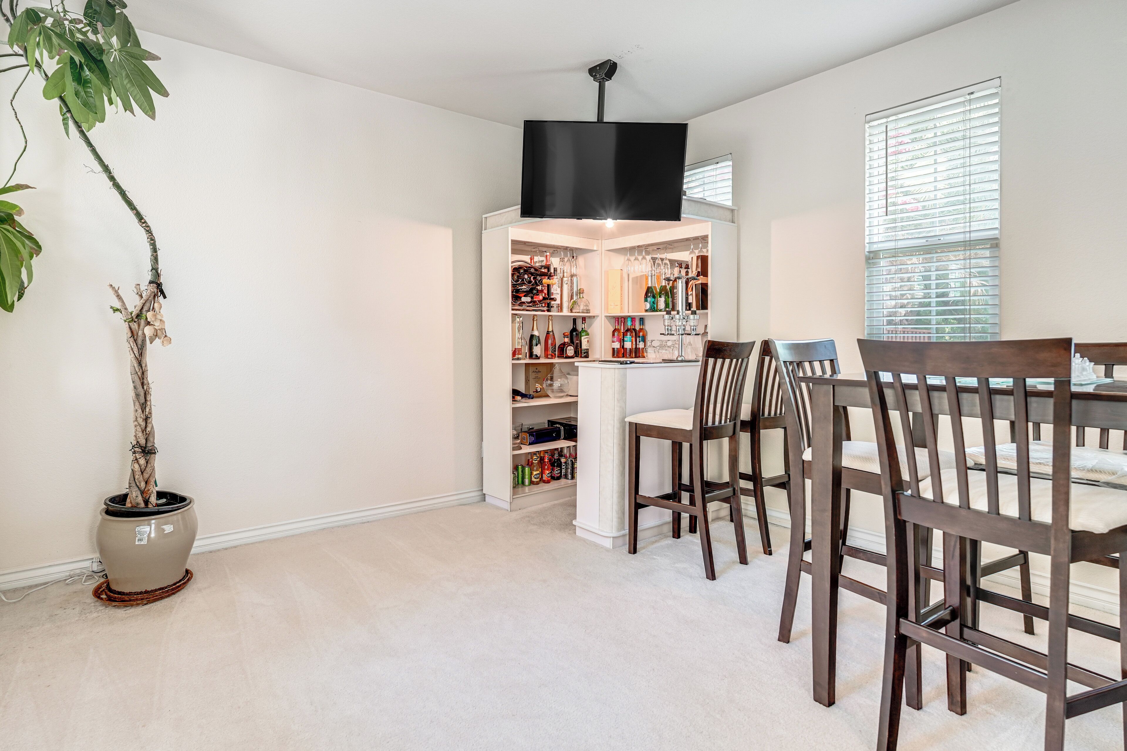 A dining area with a built-in wine rack, a potted plant, and a TV mounted on the wall.