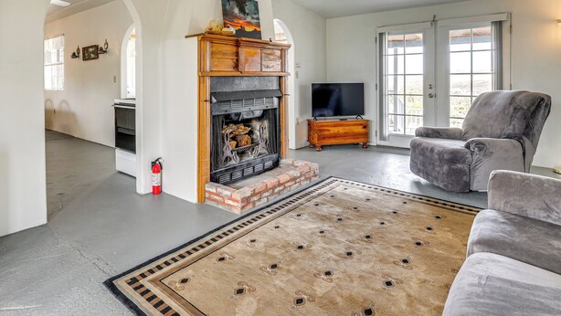Een woonkamer met een open haard, een grijze bank en een televisie.