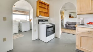 Een keuken met een fornuis, oven en houten keukenkastjes. Een raam biedt uitzicht op de bergen.