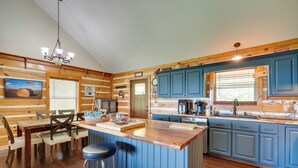 A kitchen with wooden walls, blue cabinets, a wooden island, and a chandelier. - Private Mountain Cabin Retreat Near Watts Bar Lake (Rockwood)