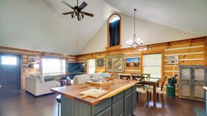 A spacious kitchen with a wooden island, a dining area with a table and chairs, a sofa, and a ceiling fan. - Private Mountain Cabin Retreat Near Watts Bar Lake (Rockwood)