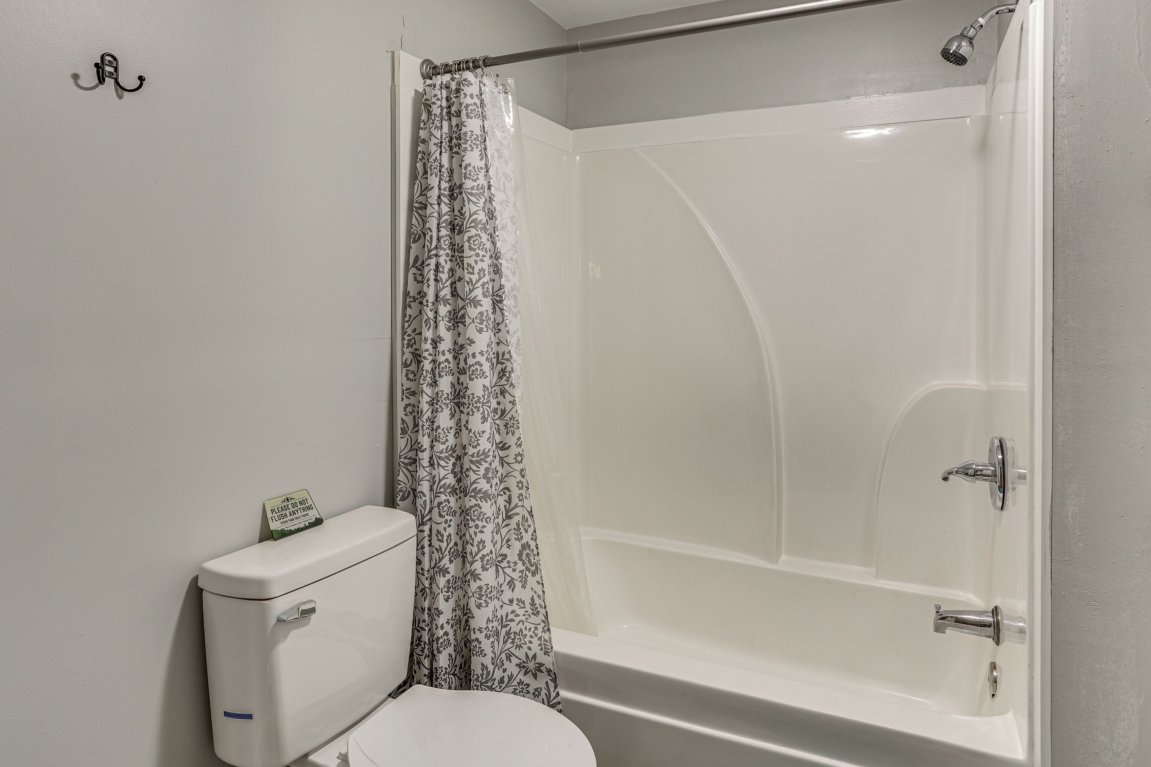 Un baño con inodoro, ducha con puerta de vidrio y un dispensador de papel higiénico en la pared.