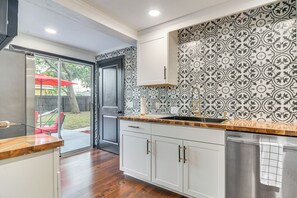 Una cocina moderna con armarios blancos, encimera de madera y un salpicadero con diseño.