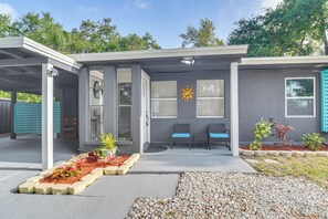 A modern building with a covered entrance, two seating areas with blue cushions, and a decorative sun emblem on the wall.