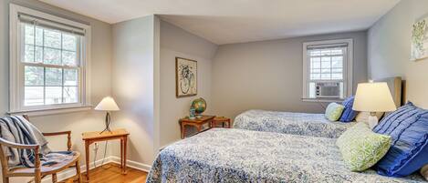 A bedroom with two beds, a chair, a table, and a globe on a nightstand.